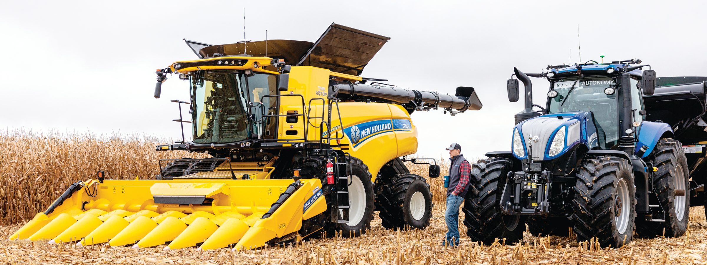 New Holland combine and tractor in a harvested corn field